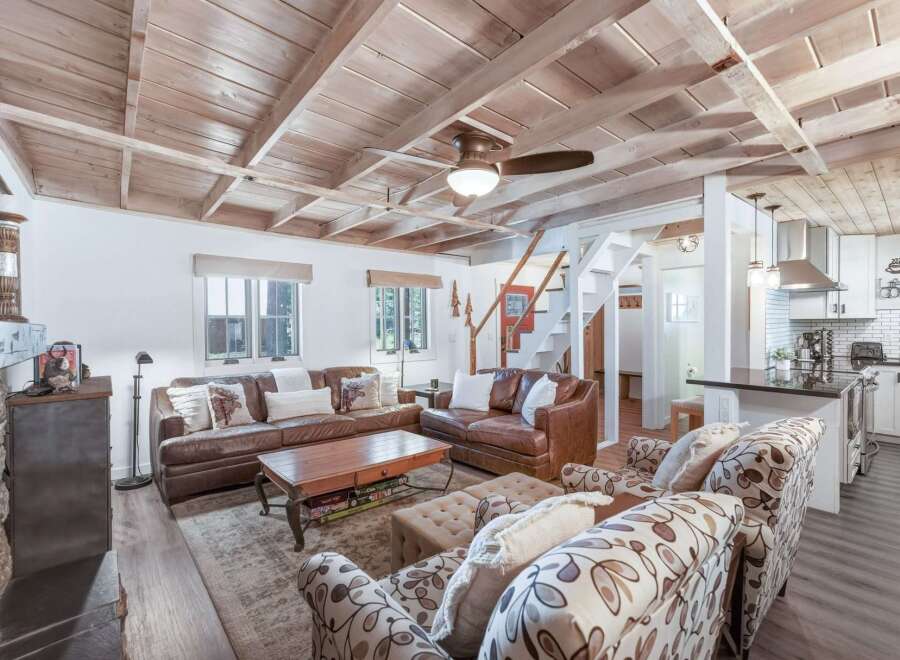 Experience rustic charm in this inviting living space, featuring a cozy leather sectional and plush accent chairs perfect for relaxation.