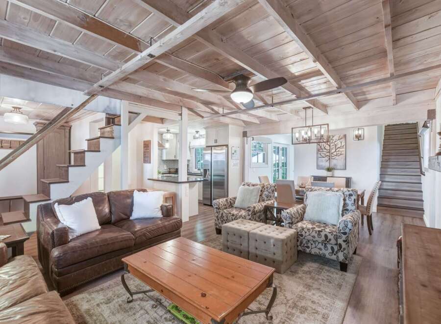 Experience rustic charm in this inviting living space, featuring exposed wooden beams and a vaulted ceiling that enhance the airy ambiance.