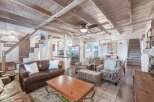 Experience rustic charm in this inviting living space, featuring exposed wooden beams and a vaulted ceiling that enhance the airy ambiance.