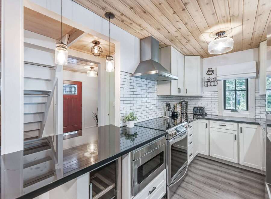This modern kitchen features sleek white cabinetry, a subway tile backsplash, and a stainless steel range hood.