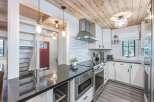 This modern kitchen features sleek white cabinetry, a subway tile backsplash, and a stainless steel range hood.