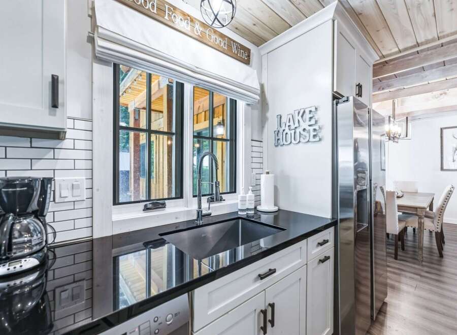 Experience the charm of this lakeside retreat, featuring a modern kitchen with sleek black countertops and white cabinetry.