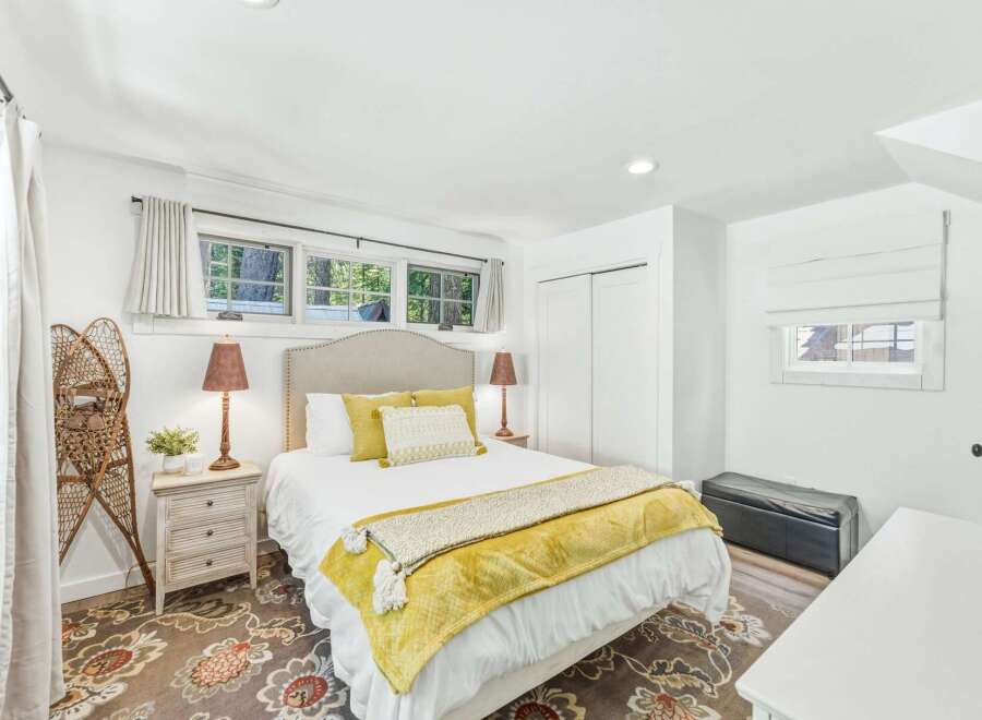 This charming bedroom features a comfortable queen-size bed adorned with yellow accents and a cozy throw.
