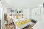 This charming bedroom features a comfortable queen-size bed adorned with yellow accents and a cozy throw.
