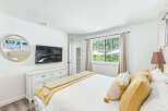 Experience comfort and style in this beautifully appointed bedroom, featuring a wall-mounted TV above a classic white dresser.