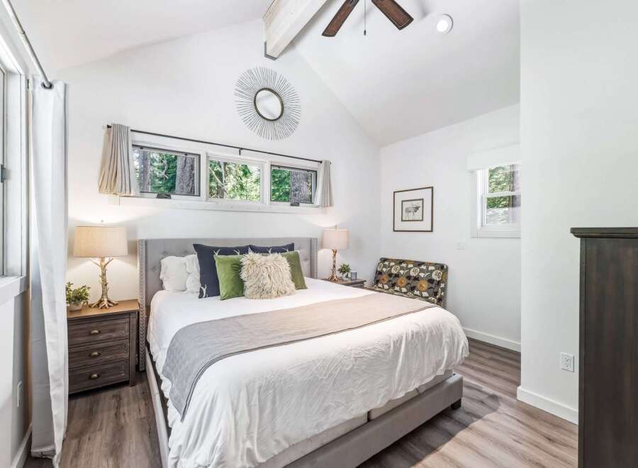 Experience serene living in this charming bedroom, featuring a comfortable queen-size bed adorned with plush pillows and a cozy throw.