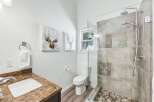 This modern bathroom features a sleek glass-enclosed shower with a dual showerhead and pebble tile flooring.