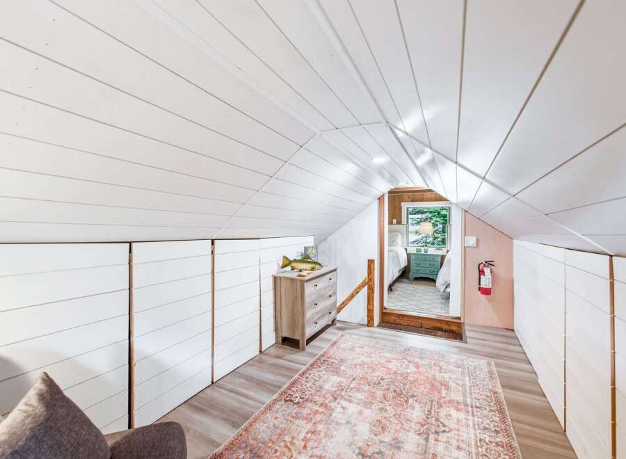 Discover this charming attic bedroom, featuring a vaulted shiplap ceiling and ample built-in storage.