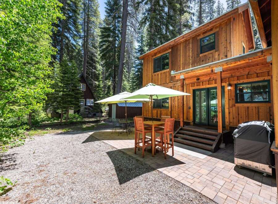 Enjoy outdoor living in this charming cabin setting, complete with a spacious patio featuring a dining set and umbrellas for shade.