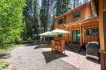 Enjoy outdoor living in this charming cabin setting, complete with a spacious patio featuring a dining set and umbrellas for shade.