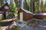 Nestled amongst tall pine trees, this charming property features a rustic brown shed with a metal roof, perfect for storage or a workshop.