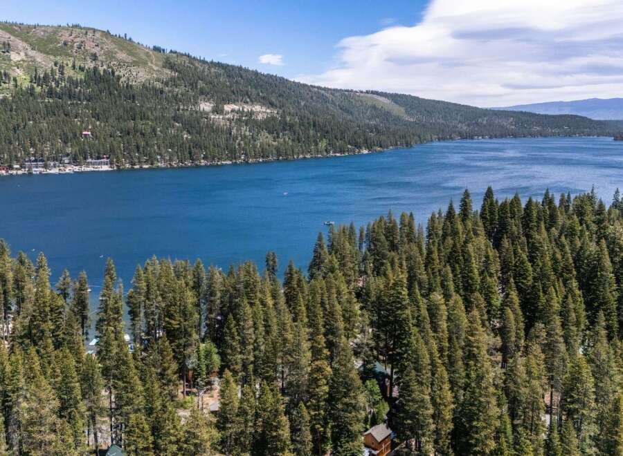 Experience the ultimate lakeside living with this stunning property offering breathtaking views of a pristine blue lake surrounded by lush green forests.