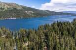 Experience the ultimate lakeside living with this stunning property offering breathtaking views of a pristine blue lake surrounded by lush green forests.