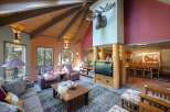 Experience rustic charm in this spacious living area, featuring a vaulted wood-beamed ceiling and a striking mounted antler decor.