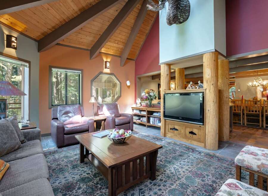 Experience rustic charm in this spacious living room, featuring a vaulted wood-beam ceiling and a cozy seating area centered around a wooden coffee table.