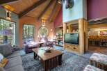 Experience rustic charm in this spacious living room, featuring a vaulted wood-beam ceiling and a cozy seating area centered around a wooden coffee table.