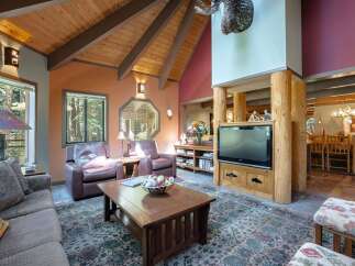 Experience rustic charm in this spacious living room, featuring a vaulted wood-beam ceiling and a cozy seating area centered around a wooden coffee table.