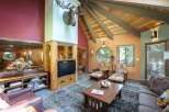 Experience rustic charm in this inviting living room, featuring a prominent stone fireplace and a vaulted wood-beamed ceiling.