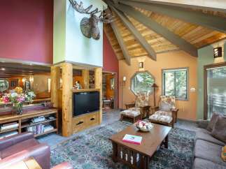 Experience rustic charm in this inviting living room, featuring a prominent stone fireplace and a vaulted wood-beamed ceiling.