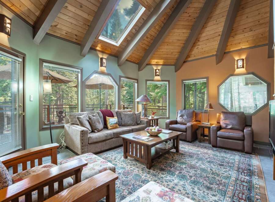 Experience rustic charm in this inviting living room, featuring a vaulted wood-beamed ceiling with a skylight that floods the space with natural light.
