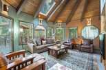 Experience rustic charm in this inviting living room, featuring a vaulted wood-beamed ceiling with a skylight that floods the space with natural light.