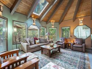 Experience rustic charm in this inviting living room, featuring a vaulted wood-beamed ceiling with a skylight that floods the space with natural light.