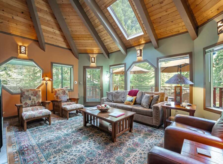 Experience rustic charm in this inviting living room, featuring a vaulted wood-beamed ceiling with skylights that flood the space with natural light.