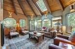 Experience rustic charm in this inviting living room, featuring a vaulted wood-beamed ceiling with skylights that flood the space with natural light.