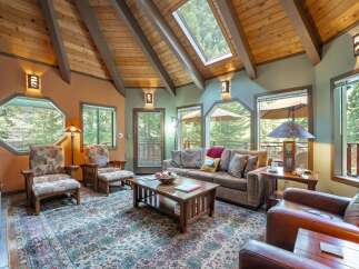 Experience rustic charm in this inviting living room, featuring a vaulted wood-beamed ceiling with skylights that flood the space with natural light.