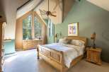 Experience rustic charm in this cozy bedroom, featuring a beautiful wooden bed and a unique vaulted ceiling with exposed beams.