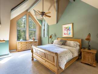 Experience rustic charm in this cozy bedroom, featuring a beautiful wooden bed and a unique vaulted ceiling with exposed beams.