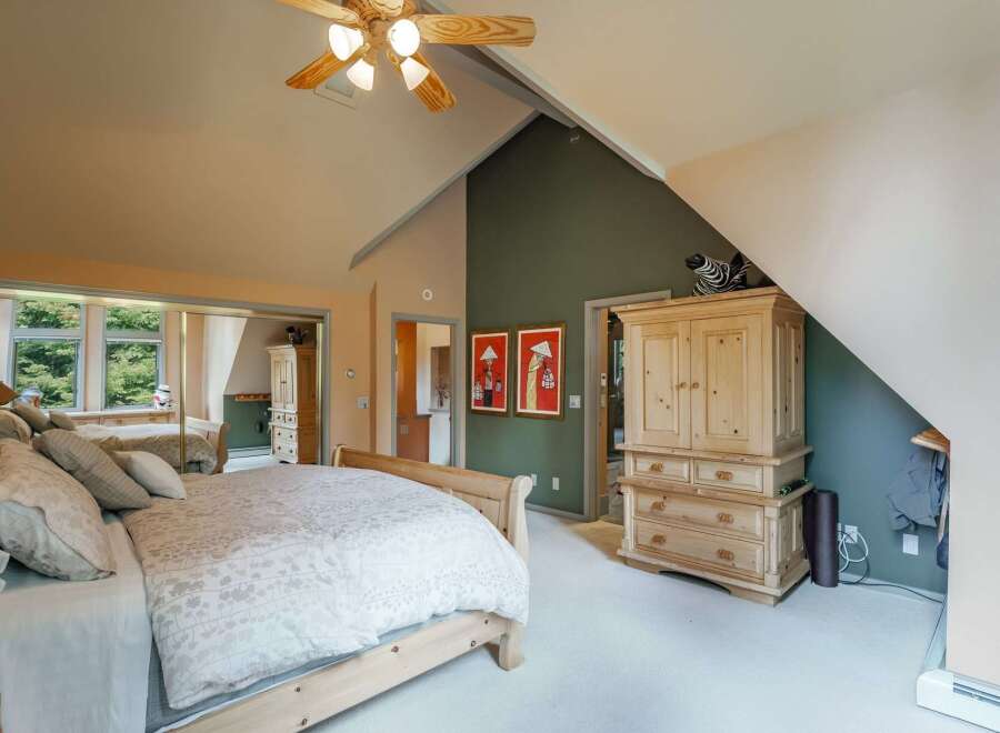 This spacious bedroom features a vaulted ceiling with a ceiling fan, creating an airy and open atmosphere.