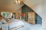 This spacious bedroom features a vaulted ceiling with a ceiling fan, creating an airy and open atmosphere.