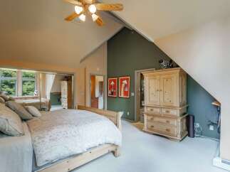 This spacious bedroom features a vaulted ceiling with a ceiling fan, creating an airy and open atmosphere.