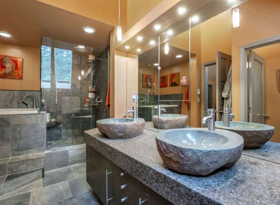 Experience luxury in this master bathroom, featuring a spacious walk-in shower with slate tile and a deep soaking tub.