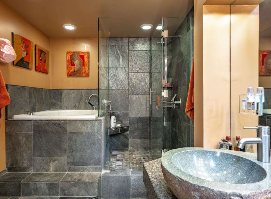 Experience luxury in this modern bathroom featuring a deep soaking tub and a spacious glass-enclosed shower with slate tile accents.