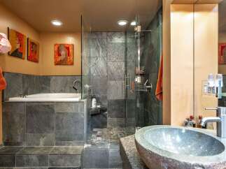 Experience luxury in this modern bathroom featuring a deep soaking tub and a spacious glass-enclosed shower with slate tile accents.