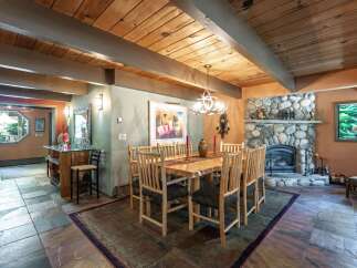 Experience rustic charm in this inviting dining area, featuring a grand stone fireplace and a warm, wood-paneled ceiling.