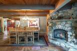 Experience rustic charm in this inviting dining area, featuring a grand stone fireplace and a unique antler chandelier.