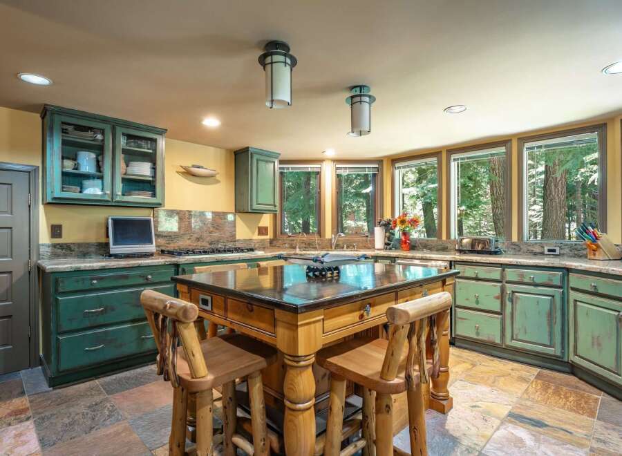 Experience rustic charm in this spacious kitchen featuring distressed green cabinetry and a large wooden island perfect for meal prep and casual dining.