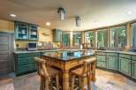 Experience rustic charm in this spacious kitchen featuring distressed green cabinetry and a large wooden island perfect for meal prep and casual dining.