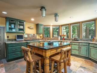 Experience rustic charm in this spacious kitchen featuring distressed green cabinetry and a large wooden island perfect for meal prep and casual dining.