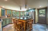 Experience rustic charm in this spacious kitchen featuring distressed green cabinetry and a large wooden island with bar seating.