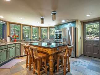 Experience rustic charm in this spacious kitchen featuring distressed green cabinetry and a large wooden island with bar seating.