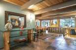 Experience rustic charm in this spacious dining and living area, featuring a stunning wood-beamed ceiling and a unique log-supported glass console table.