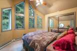Experience serene living in this charming bedroom, bathed in natural light from unique, angular windows offering picturesque forest views.