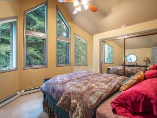 Experience serene living in this charming bedroom, bathed in natural light from unique, angular windows offering picturesque forest views.