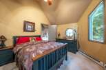 Discover this charming bedroom featuring a cozy queen-size bed adorned with a luxurious paisley comforter and vibrant red pillows.