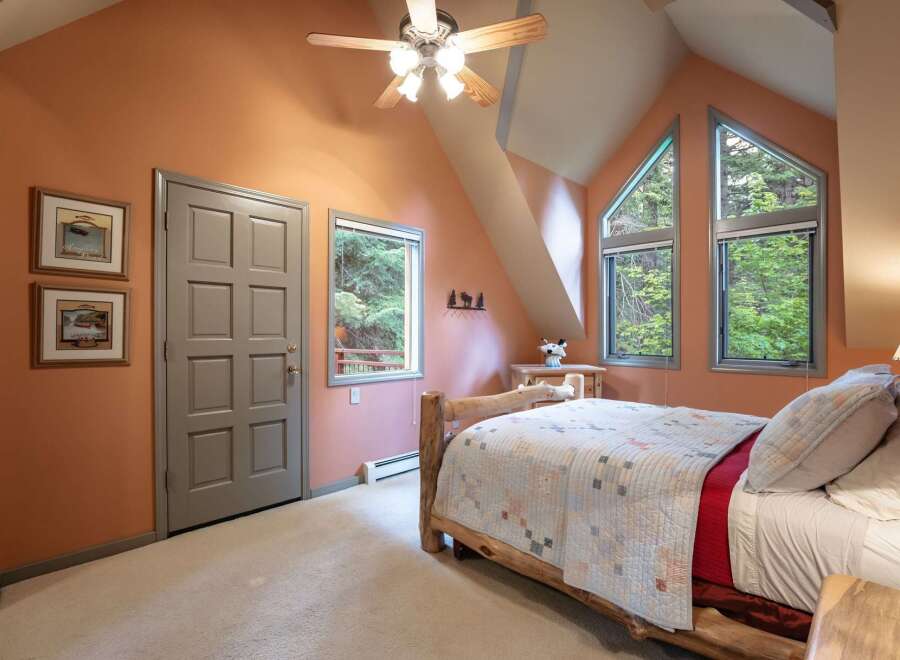 Experience rustic charm in this cozy bedroom featuring a unique log bed and a tranquil forest view.