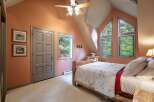 Experience rustic charm in this cozy bedroom featuring a unique log bed and a tranquil forest view.